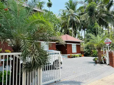 a white fence in front of a house with palm trees at Redstone Villa in Tāzhekkod