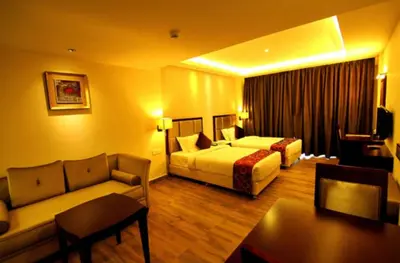a hotel room with two beds and a couch at Paravoor Galaxy Hotel in Cherai Beach