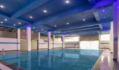 a large swimming pool in a building with blue lighting at Treebo The Rove with Swimming Pool in Madikeri