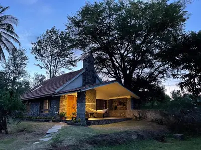 a small stone house with a tree behind it at Captain's Cabin in Masinagudi