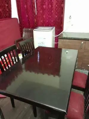 a wooden table with chairs and a table with a glass top at Ohm Shanthi Kudil in Kodaikānāl