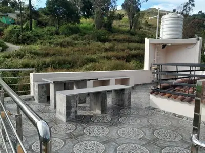 a bench sitting on top of a patio with a field at Ohm Shanthi Kudil in Kodaikānāl