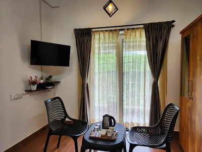 a living room with a table and chairs and a window at Cloud & Mist Inn-Stay with Mountain Views in Kotagiri, Near Ooty in Kotagiri