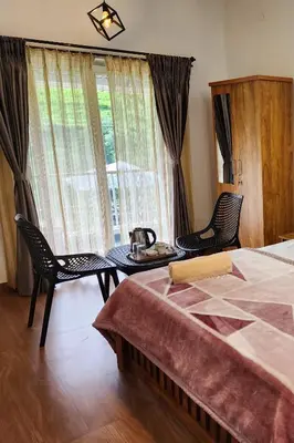 a bedroom with a bed and a table and chairs at Cloud & Mist Inn-Stay with Mountain Views in Kotagiri, Near Ooty in Kotagiri