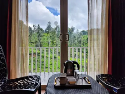 a tea kettle on a table in front of a window at Cloud & Mist Inn-Stay with Mountain Views in Kotagiri, Near Ooty in Kotagiri