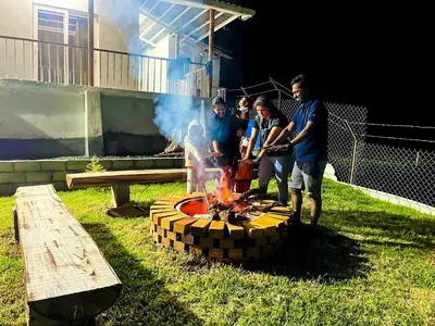 a group of people standing around a fire pit at Cloud & Mist Inn-Stay with Mountain Views in Kotagiri, Near Ooty in Kotagiri
