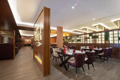 a restaurant with tables and chairs and a fireplace at Jenneys Residency in Coimbatore