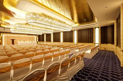 an empty banquet hall with white chairs and chandeliers at Jenneys Residency in Coimbatore