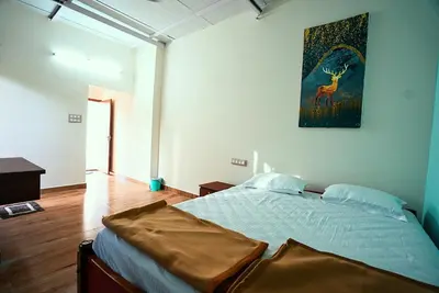 a bedroom with a bed with a painting on the wall at Gandhada Goodu Retreat in Kanakapura