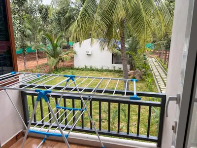 a bed on a balcony with a view of a yard at Gandhada Goodu Retreat in Kanakapura