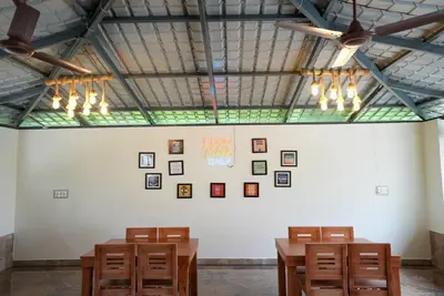 a room with wooden tables and pictures on a wall at Gandhada Goodu Retreat in Kanakapura