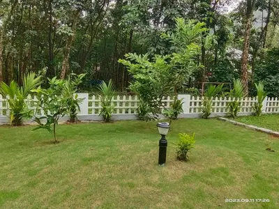 a light in a yard with a white fence at Family Cottage at Merlys Fruit Garden, Thattekkad in Kotamangalam