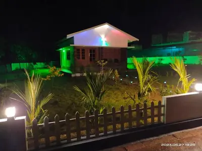 a house lit up at night with green lights at Family Cottage at Merlys Fruit Garden, Thattekkad in Kotamangalam