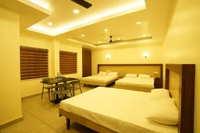 a hotel room with two beds and a table at SREENARAYANA TOURIST HOME in Guruvāyūr