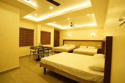 a hotel room with two beds and a table at SREENARAYANA TOURIST HOME in Guruvāyūr