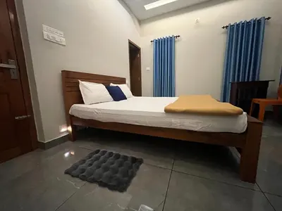 a bedroom with a bed with blue curtains at Chaithanya Residency Near to NIT Kozhikode in Kunnamangalam