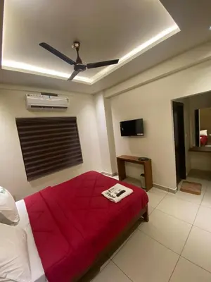 a bedroom with a red bed with a ceiling fan at Redbell Suites Kizhisseri in Kondotti