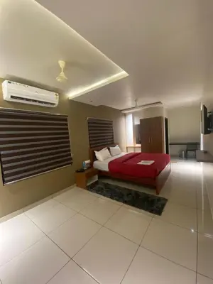 a bedroom with a bed with a red bedspread at Redbell Suites Kizhisseri in Kondotti