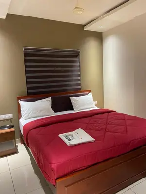 a bedroom with a red bed with a book on it at Redbell Suites Kizhisseri in Kondotti