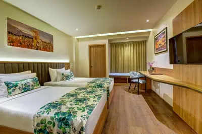 a hotel room with two beds and a desk at Regenta Central Javaji Mysore in Mysore