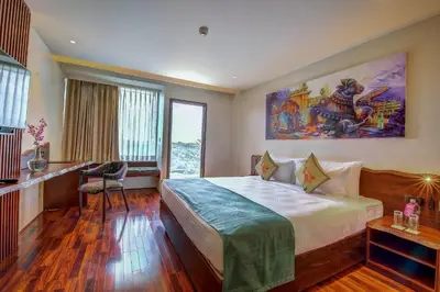 a hotel room with a bed and a painting on the wall at Regenta Central Javaji Mysore in Mysore
