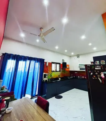a living room with a table and a ceiling fan at Tranquil Haven Villa Homestay in Mysore