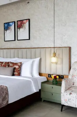 a bedroom with a bed and a chair at Flora Misty Falls Athirappilly in Athirappilly