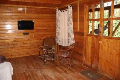 a room with two chairs and a television in a log cabin at Coorg Northbreeze Wooden Stay in Madikeri