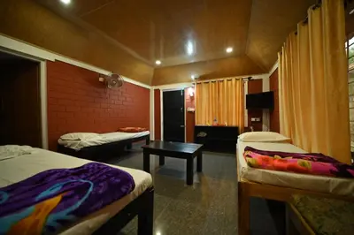 a room with two beds and a table in it at Coorg HomeStay Resort in Kushālnagar
