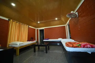 a room with three beds in a red brick wall at Coorg HomeStay Resort in Kushālnagar