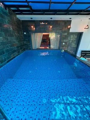 a large indoor swimming pool with blue water at Agasthya Private Pool & Park villa in Sultan Bathery