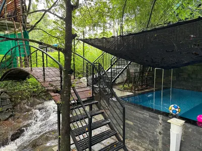 a staircase leading to a swimming pool next to a river at Agasthya Private Pool & Park villa in Sultan Bathery