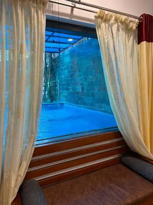 a swimming pool seen through a window with curtains at Agasthya Private Pool & Park villa in Sultan Bathery
