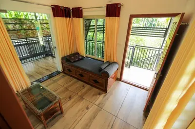 an empty living room with a couch and a balcony at Agasthya Private Pool & Park villa in Sultan Bathery