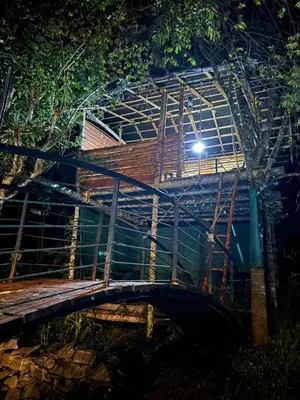 a wooden bridge at night with a light at Agasthya Private Pool & Park villa in Sultan Bathery