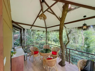 a room with a table and chairs on a balcony at Coffee Cradle Wayanad Luxuorios Private Tree House - Inside 2 Acre Coffee Plantation in Mananthavady