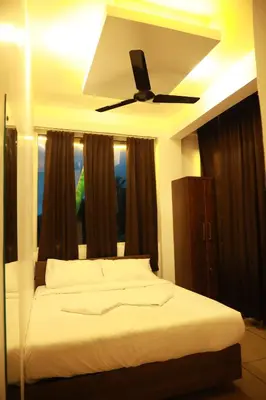 a bedroom with a bed with a ceiling fan at AROMA INN in Kalpetta