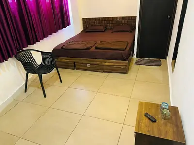 a bedroom with a bed and a chair and a table at AROMA INN in Kalpetta