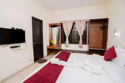 a bedroom with a white bed and a flat screen tv at Tulips Resorts - Elkhill in Ooty