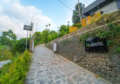 a stone wall with a sign on it next to a street at Munnar Majestic Resort with Pool in Munnar