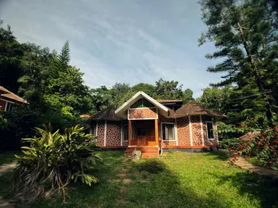 a small house in a yard with a grass field at Mahout Resort Wayanad - An Experiential Jungle Stay with Waterfall in Kalpetta