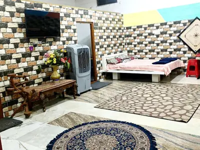 a room with a bed and a tv on a wall at Sahara Family Homestay in Mysore
