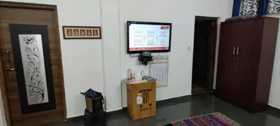 a room with a tv on the wall and a box at Sandy 4 Bhk Homestay - Only Adults Allowed in Ooty