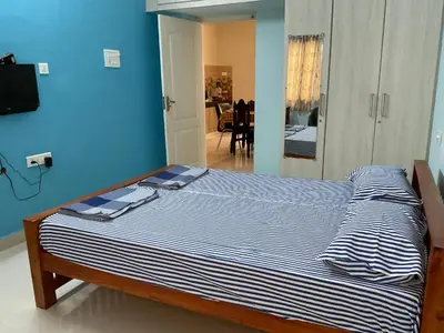 a bed in a bedroom with a blue wall at Shantham Service Apartments, Indumanagar, Coimbatore in Coimbatore