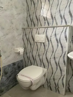 a bathroom with a white toilet in a room at Shantham Service Apartments, Indumanagar, Coimbatore in Coimbatore