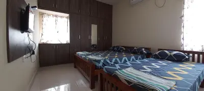 a bedroom with two beds and a tv on the wall at Shantham Service Apartments, Indumanagar, Coimbatore in Coimbatore