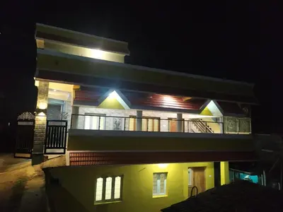 a large yellow house with a balcony at night at Golden View Cottage Ooty in Ooty