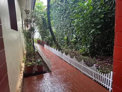 a white fence next to a garden with plants at Kanjira house in Ooty