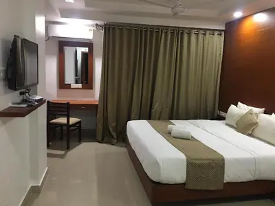 a bedroom with a bed and a desk and a television at Nakshatra Emerald in Guruvāyūr