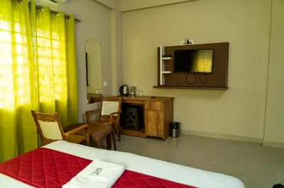 a bedroom with a bed and a table and a television at DREAMS AIRPORT RESIDENCY in Nedumbassery